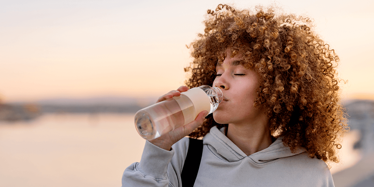 women outside drinking water from bottle
