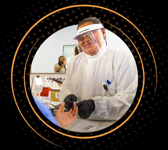 Un sonriente profesional sanitario de BioLife vestido con equipo de protección examina a un donante.